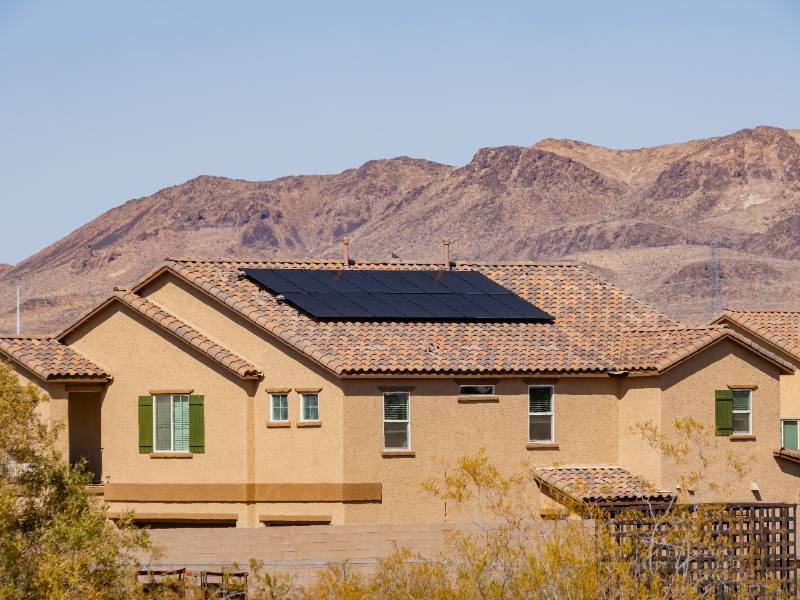 Modern tan home with solar panels on roof in desert landscape